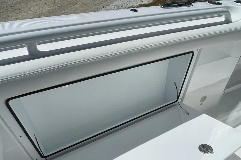 Slide: The Image of 2026 Everglades 285 Center Console boat interior detail, featuring sleek white design and storage compartment. - 12