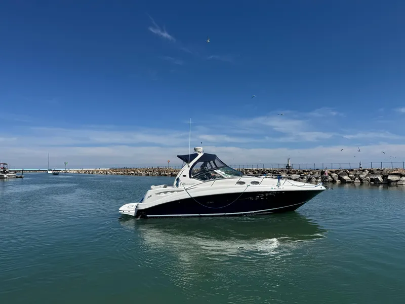 Slide: The Image of 2004 Sea Ray 320 Sundancer cruising in a calm harbor under a clear blue sky. - 13