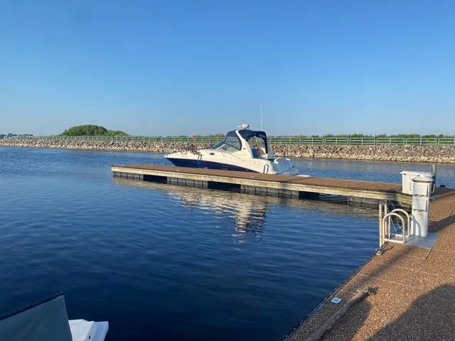 Slide: The Image of 2004 Sea Ray 320 Sundancer docked on calm water under clear blue sky. - 24