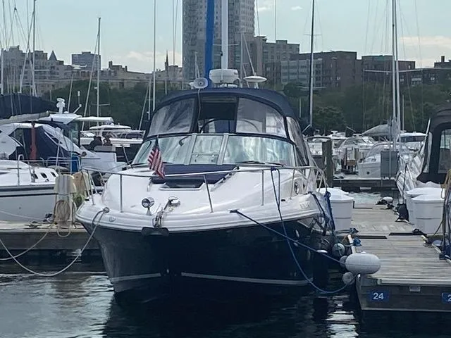 Slide: The Image of 2004 Sea Ray 320 Sundancer docked at marina with city skyline in background. - 26