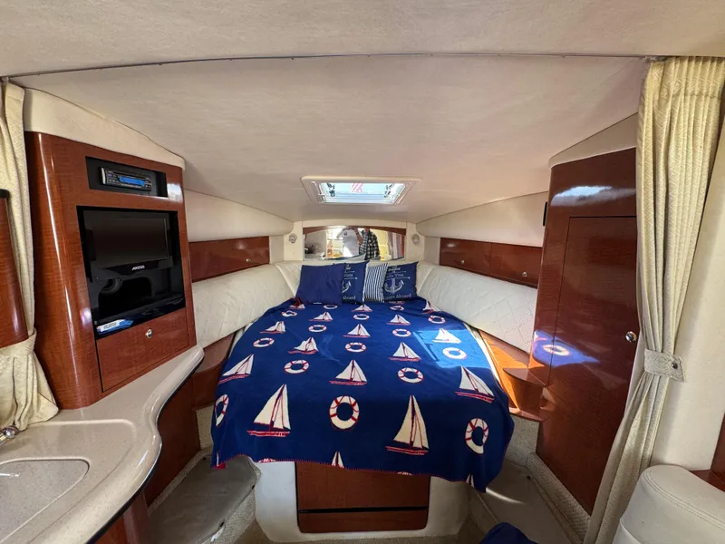 Slide: The Image of 2004 Sea Ray 320 Sundancer cabin with nautical-themed bedding and wood accents. - 42