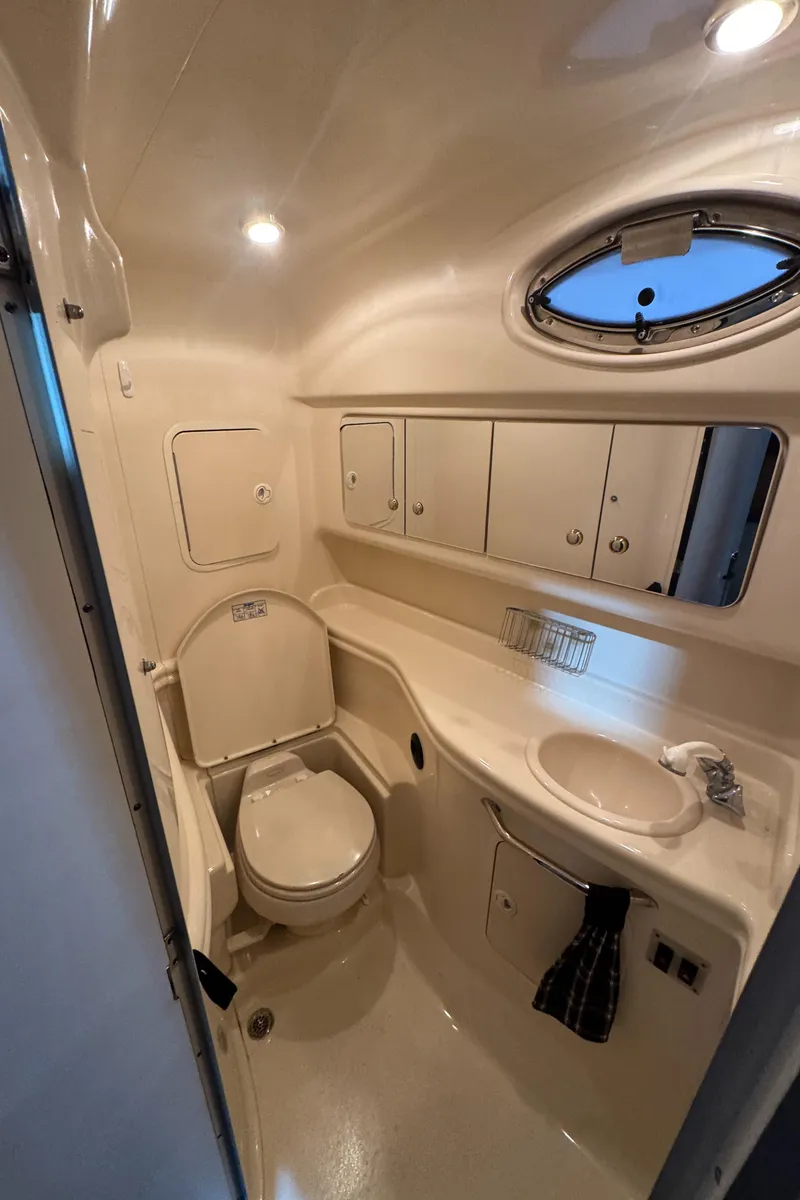 Slide: The Image of 2004 Sea Ray 320 Sundancer bathroom with toilet, sink, and storage cabinets. - 46