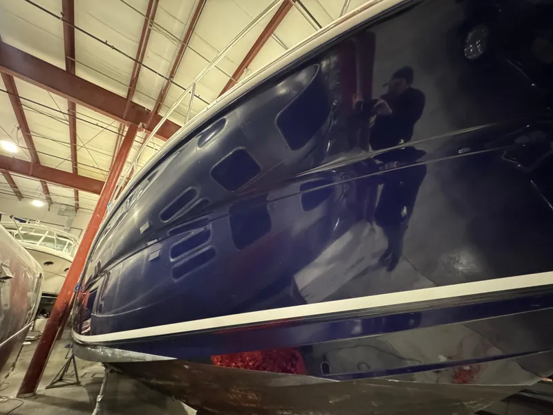 Slide: The Image of 2004 Sea Ray 320 Sundancer in storage, showcasing sleek blue hull design. - 58