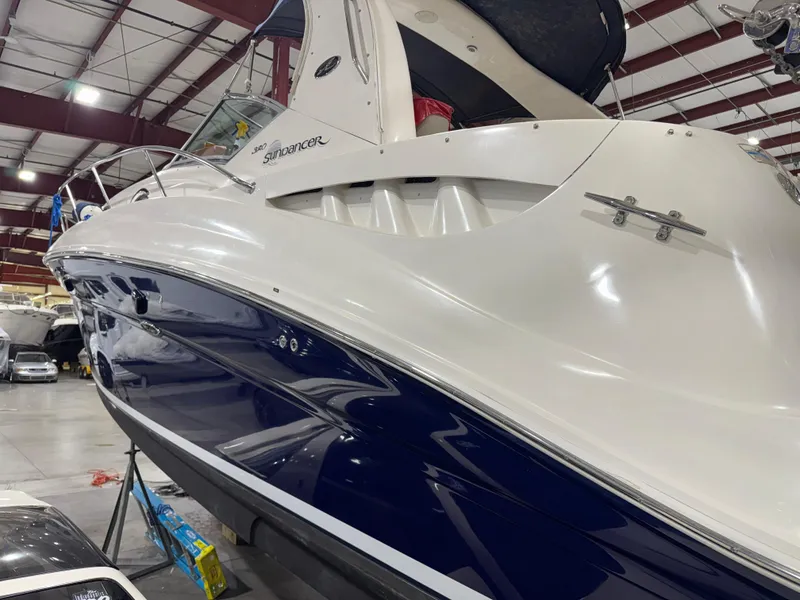 Slide: The Image of 2004 Sea Ray 320 Sundancer boat in indoor storage, showcasing sleek design and white-blue exterior. - 59