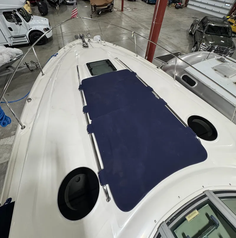 Slide: The Image of 2004 Sea Ray 320 Sundancer boat deck with blue cover in a storage facility. - 63