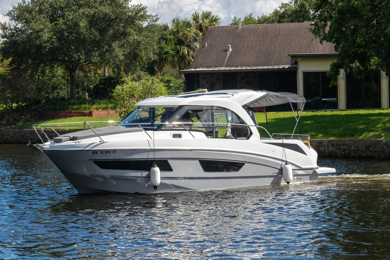 The Image of 2025 Beneteau Antares 9 motorboat cruising on a serene waterway near a house. - 0