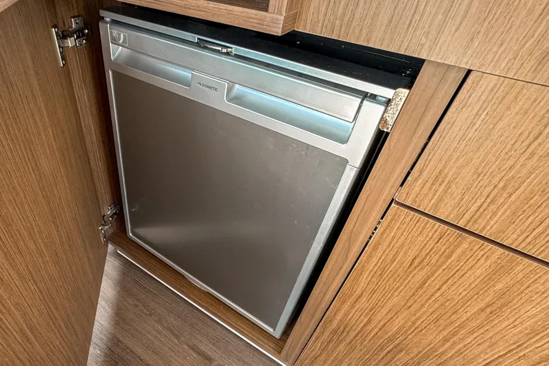 Slide: The Image of Built-in fridge on 2025 Beneteau Antares 9 yacht, featuring sleek wood cabinetry. - 13