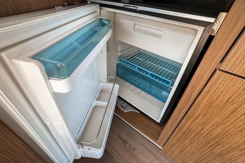 Slide: The Image of Open refrigerator inside 2025 Beneteau Antares 9 boat, featuring wooden cabinetry. - 14