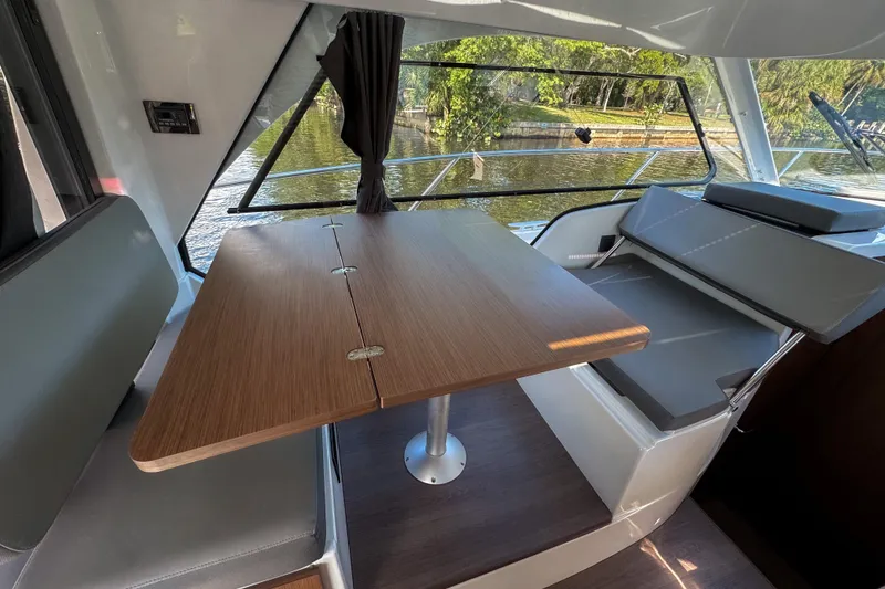 Slide: The Image of Interior of 2025 Beneteau Antares 9, featuring a wooden table and seating by a window. - 17