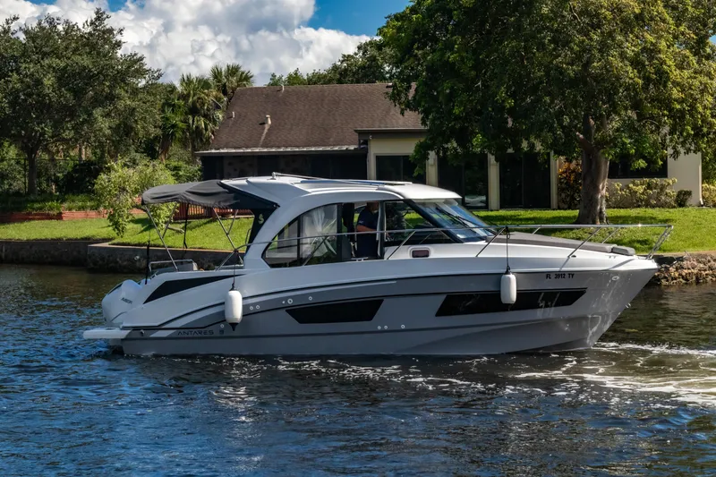Slide: The Image of 2025 Beneteau Antares 9 cruising on a scenic waterway near a house. - 27