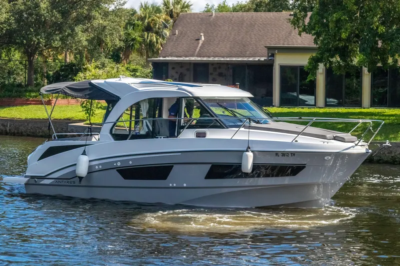 Slide: The Image of 2025 Beneteau Antares 9 cruising on a serene waterway near a house. - 4