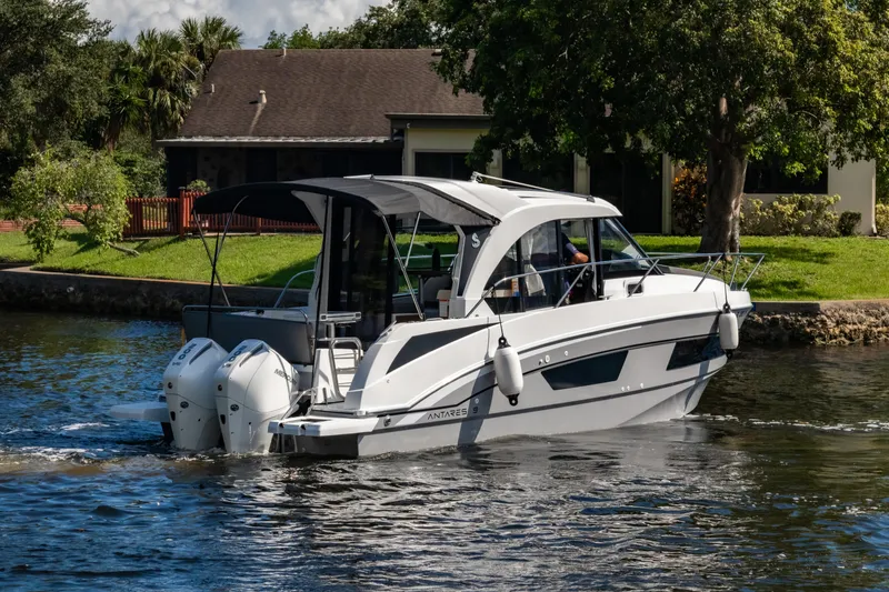 Slide: The Image of 2025 Beneteau Antares 9 motorboat cruising on a scenic waterway near a house. - 6