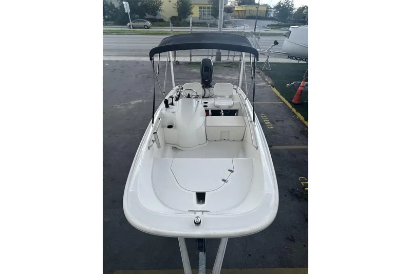 Slide: The Image of 2011 Boston Whaler 160 Super Sport boat with canopy, parked on pavement. - 14
