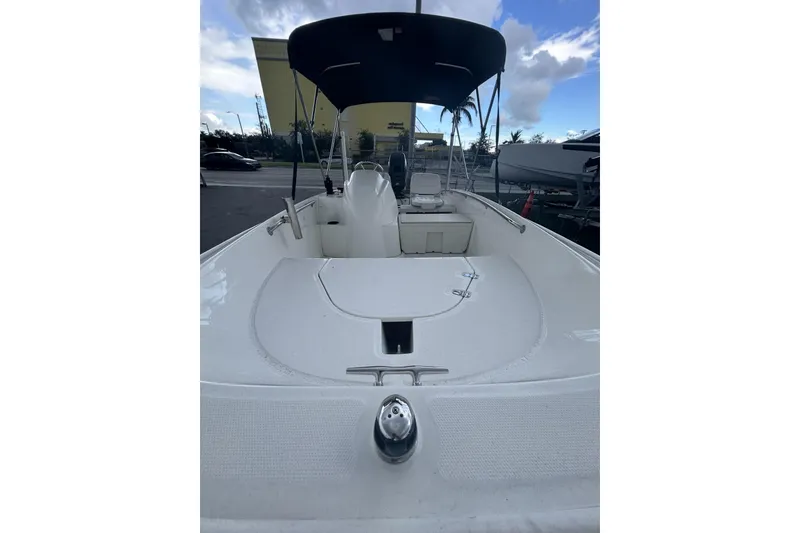 Slide: The Image of 2011 Boston Whaler 160 Super Sport boat with canopy, docked under a blue sky. - 15