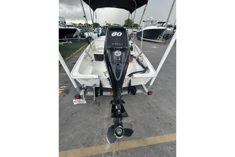 Slide: The Image of 2011 Boston Whaler 160 Super Sport with outboard motor, parked in a marina. - 20