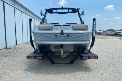 Slide: The Image of 2026 ATX Surf Boats 20 Type-S, rear view, parked on gravel near storage units. - 5