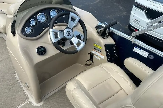 Slide: The Image of 2014 Manitou 24 Oasis SR boat dashboard with steering wheel and beige seating. - 11