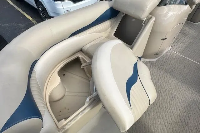 Slide: The Image of 2014 Manitou 24 Oasis SR boat interior with beige and blue seating, open storage compartment. - 17