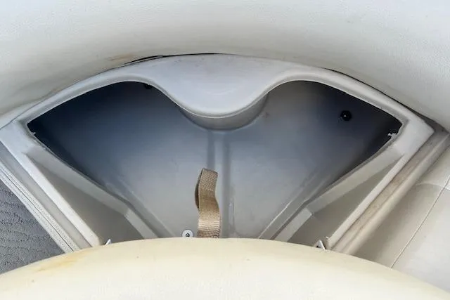 Slide: The Image of 2014 Manitou 24 Oasis SR boat storage compartment with beige interior and strap. - 25