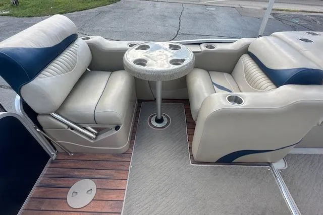 Slide: The Image of 2014 Manitou 24 Oasis SR boat interior with cushioned seating and round table. - 28
