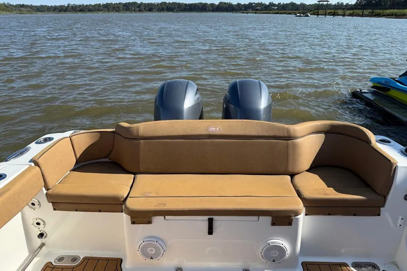 Slide: The Image of 2022 Sea Hunt Ultra 275 SE boat with tan seating, dual engines, on a calm lake. - 14