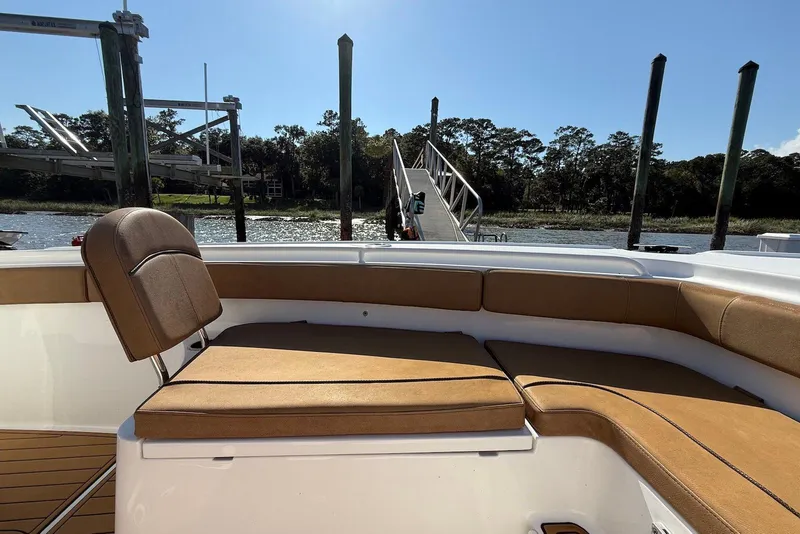 Slide: The Image of 2022 Sea Hunt Ultra 275 SE boat interior with tan seating, docked by a scenic river. - 19