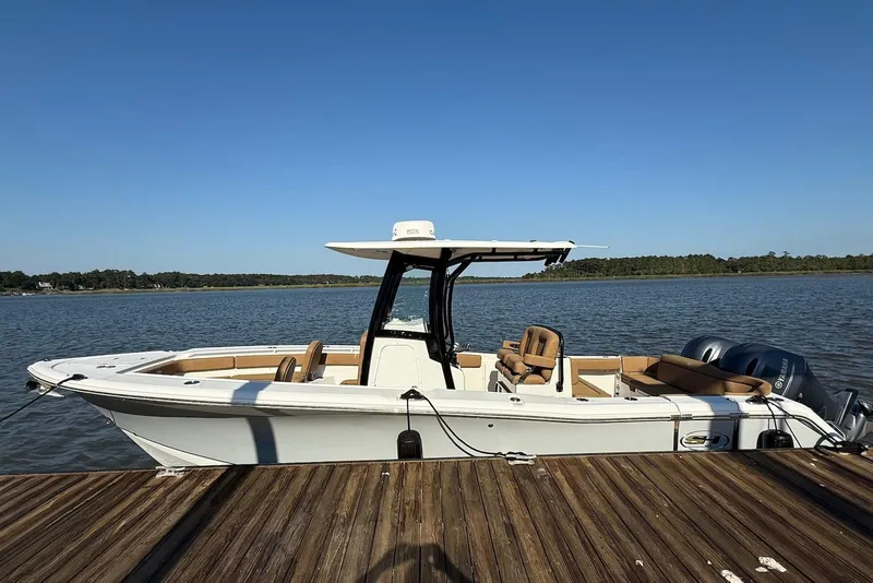 Slide: The Image of 2022 Sea Hunt Ultra 275 SE boat docked on a sunny day by the water. - 2