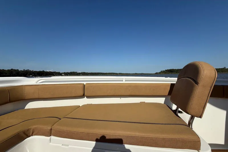 Slide: The Image of 2022 Sea Hunt Ultra 275 SE boat interior with tan seating, clear blue sky, and water view. - 22