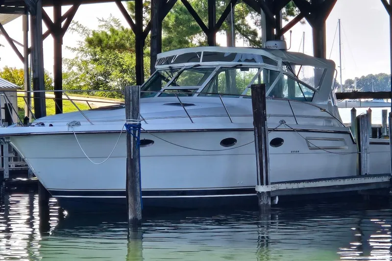 Slide: The Image of 1996 Tiara Yachts 3700 Open docked under a wooden shelter on calm water. - 11
