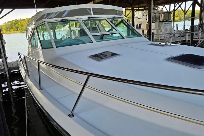 Slide: The Image of 1996 Tiara Yachts 3700 Open docked under a covered marina, featuring clear enclosure. - 17