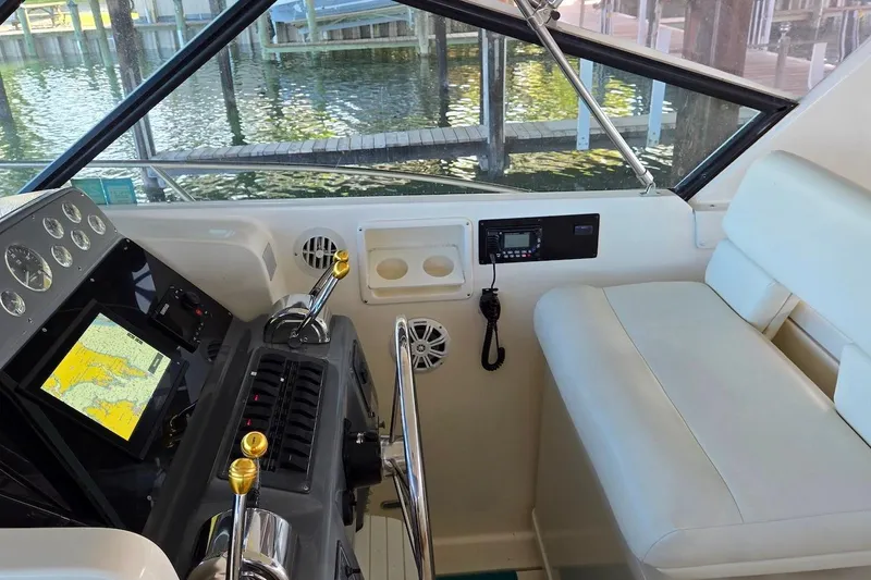 Slide: The Image of 1996 Tiara Yachts 3700 Open docked under a wooden shelter by the water. - 23