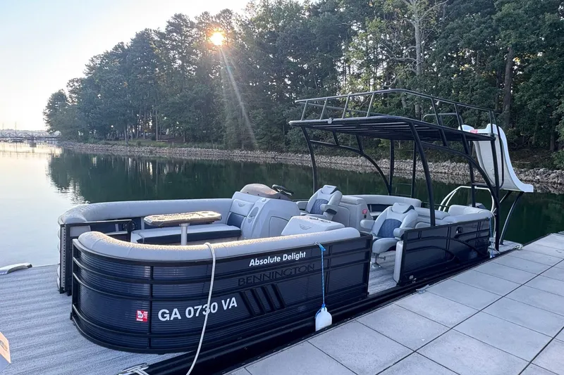The Image of 2025 Bennington 26 L Top Deck pontoon boat docked by a serene lake. - 0