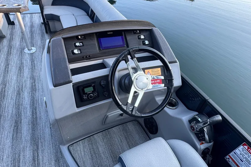 Slide: The Image of 2025 Bennington 26 L Top Deck boat interior with steering console and cushioned captain's chair. - 4