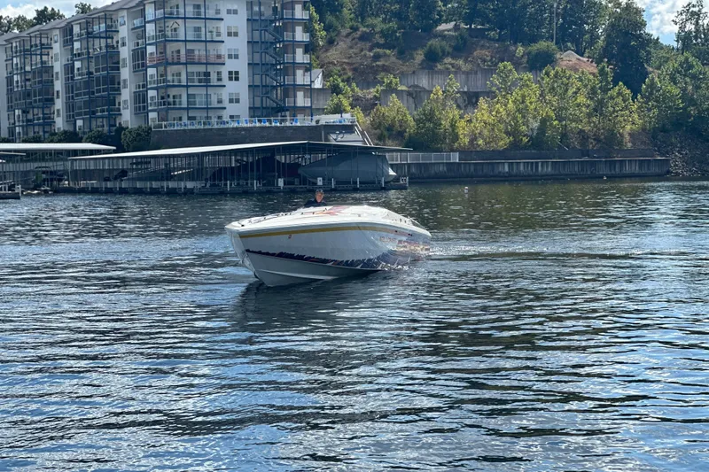 Slide: The Image of 1995 Excel Scarab 43 boat cruising on a scenic waterfront near modern buildings. - 10