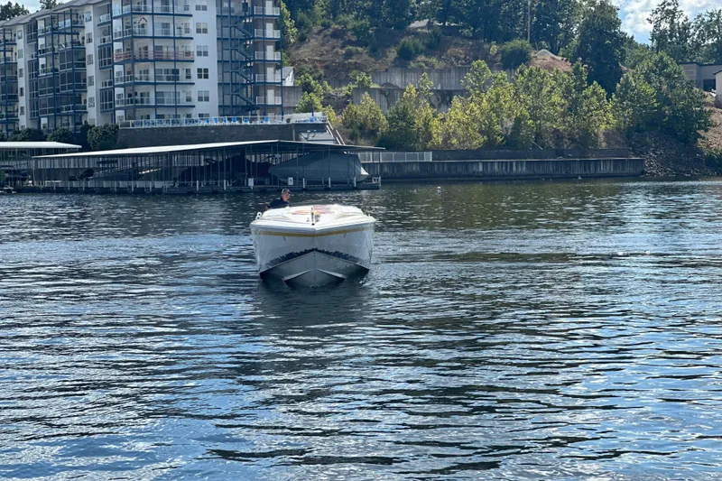 Slide: The Image of 1995 Excel Scarab 43 boat cruising on a calm river near modern apartments. - 11