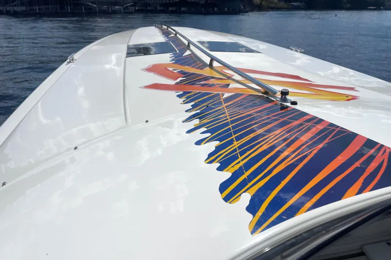 Slide: The Image of 1995 Excel Scarab 43 boat with vibrant graphic design on deck, cruising on water. - 14