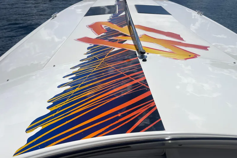 Slide: The Image of 1995 Excel Scarab 43 boat with vibrant orange and blue graphics on deck. - 15