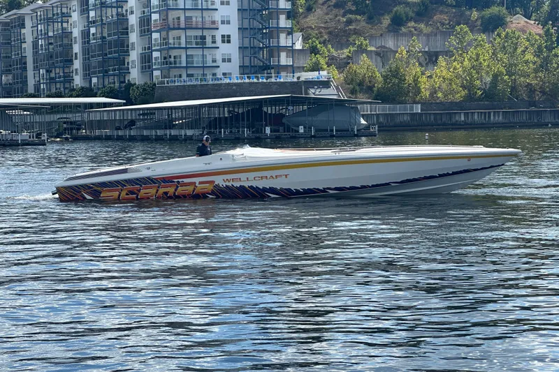 Slide: The Image of 1995 Excel Scarab 43 boat cruising on a river near modern apartments. - 5