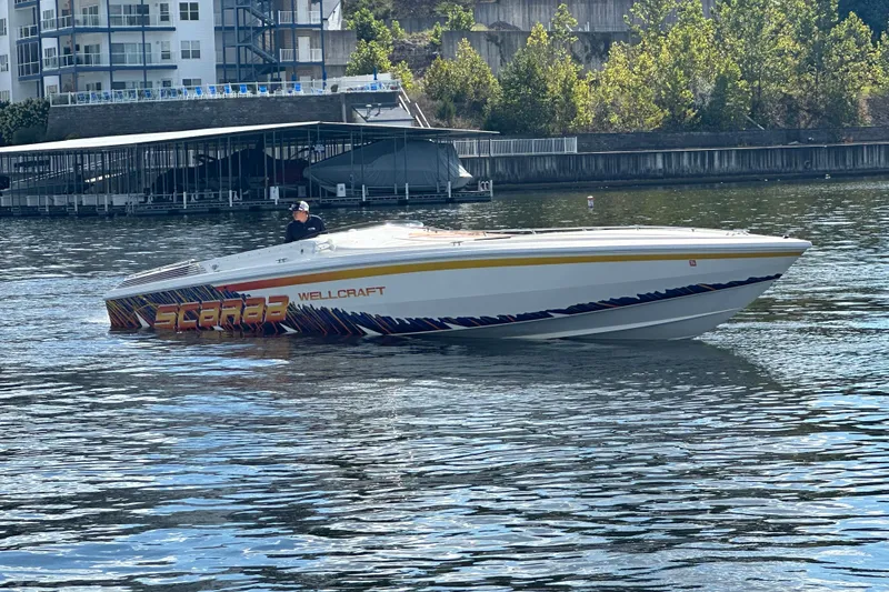 Slide: The Image of 1995 Excel Scarab 43 speedboat on water near dock, vibrant graphics, sunny day. - 7