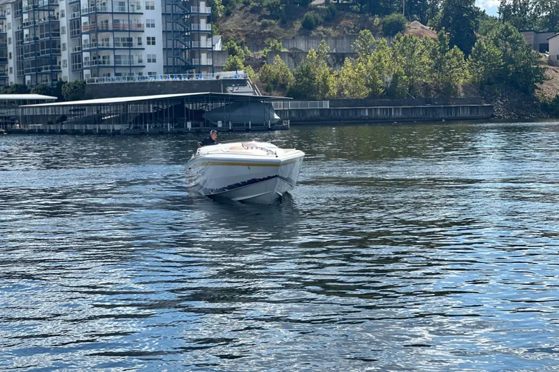 Slide: The Image of 1995 Excel Scarab 43 boat cruising on a calm river near waterfront buildings. - 9