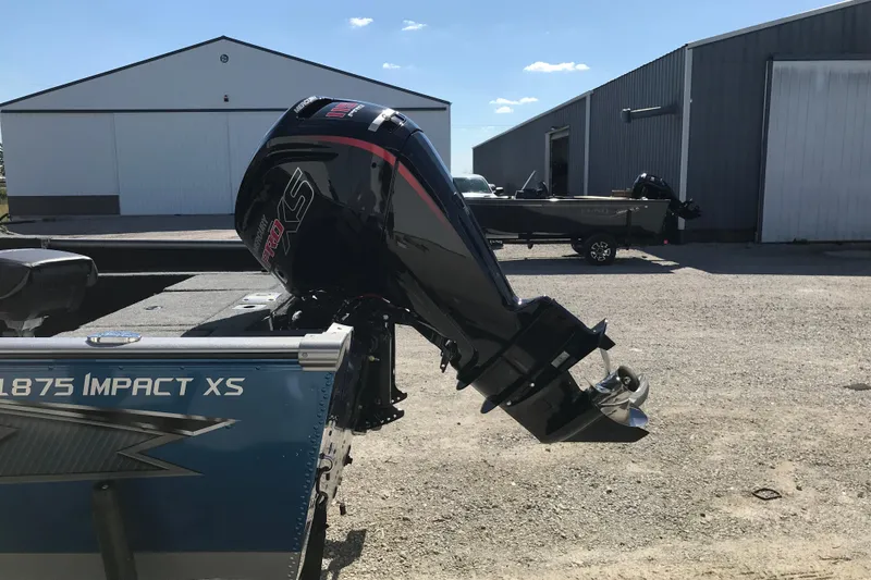 Slide: The Image of 2026 Lund 1875 Impact XS SS boat displayed in showroom with modern design. - 2