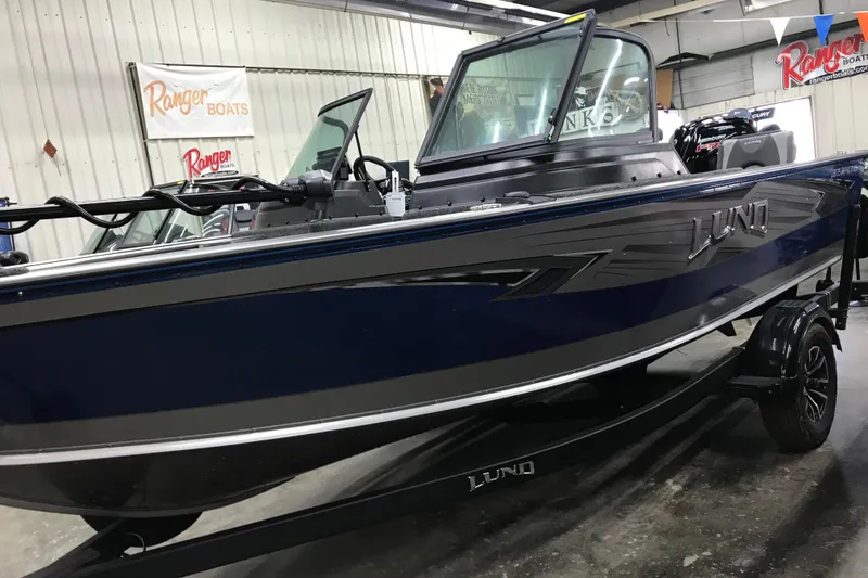Slide: The Image of 2026 Lund 1875 Impact XS SS boat in showroom, blue exterior, on trailer. - 9