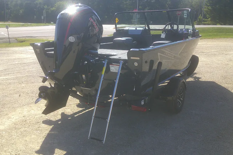 Slide: The Image of 2026 Lund 1775 Adventure Sport boat with outboard motor and ladder, parked outdoors. - 16