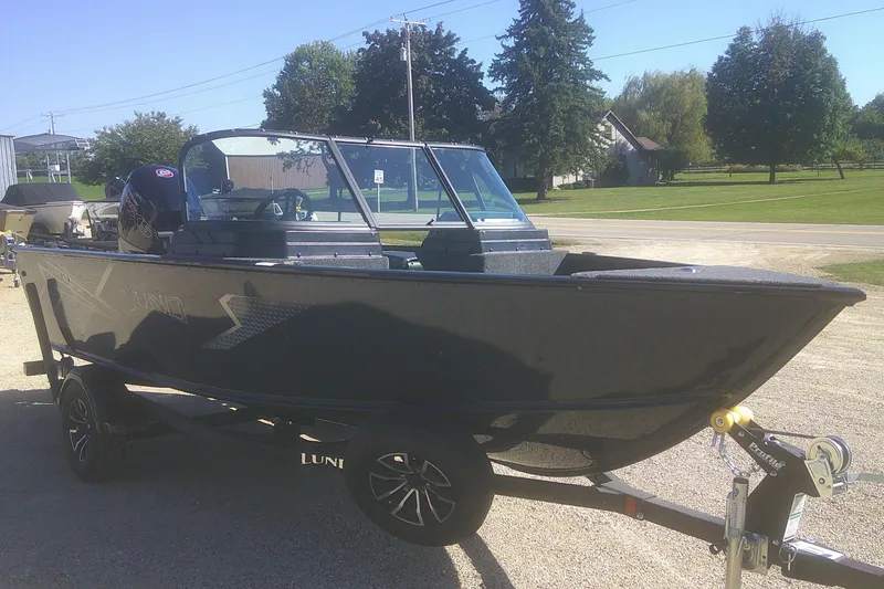 Slide: The Image of 2026 Lund 1775 Adventure Sport boat on trailer, parked outdoors on a sunny day. - 2