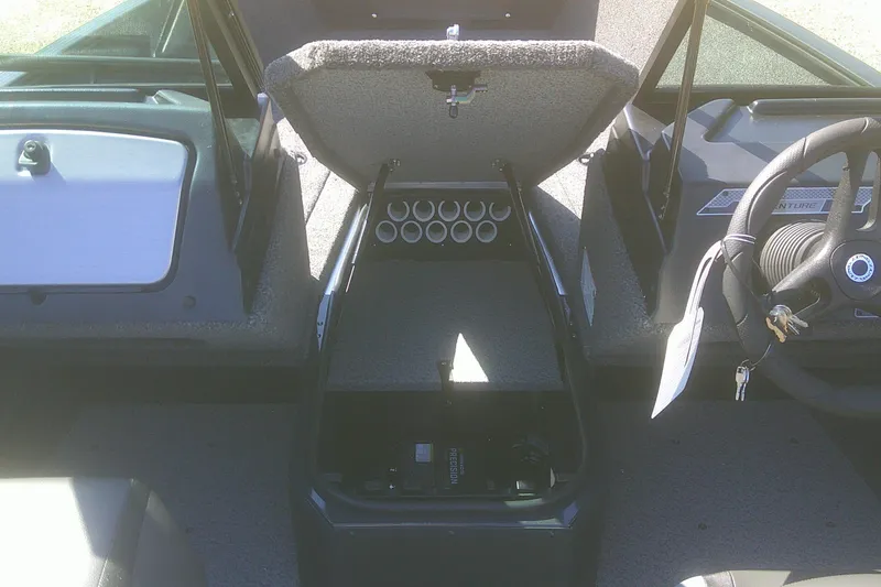 Slide: The Image of 2026 Lund 1775 Adventure Sport boat interior with open storage compartment and steering wheel. - 5