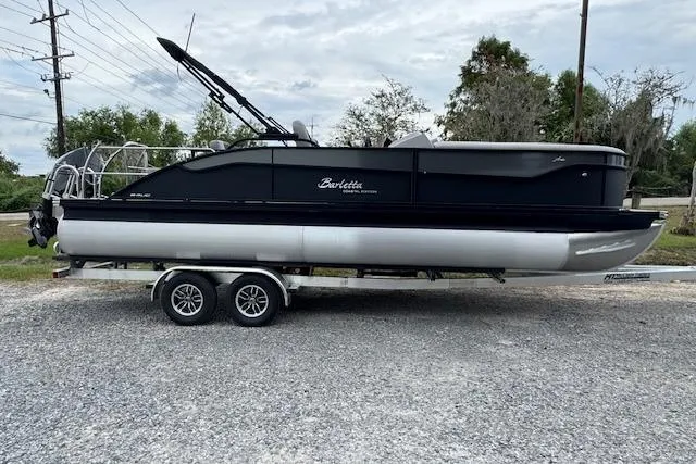 The Image of 2026 Barletta ARIA 24 UC pontoon boat on a trailer, parked outdoors. - 1