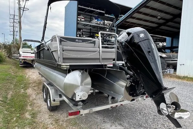 Slide: The Image of 2026 Barletta ARIA 24 UC pontoon boat on trailer, parked near a storage facility. - 5