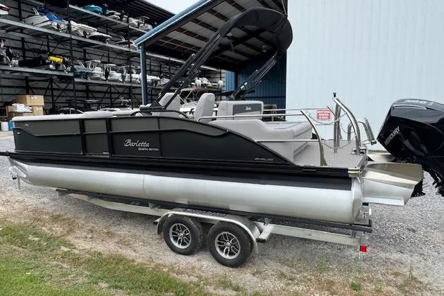 Slide: The Image of 2026 Barletta ARIA 24 UC pontoon boat on trailer, parked near storage facility. - 6