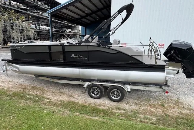 Slide: The Image of 2026 Barletta ARIA 24 UC pontoon boat on trailer, parked outdoors near storage facility. - 7