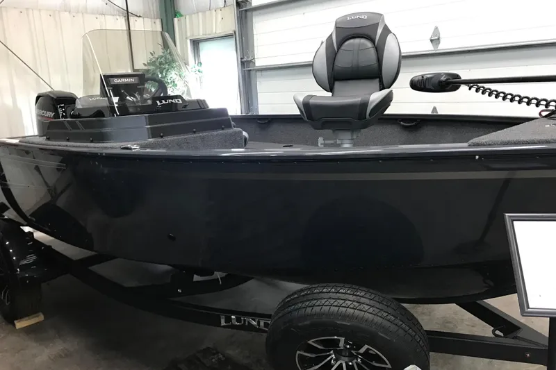 Slide: The Image of 2026 Lund 1650 Rebel XL SS boat in showroom, featuring sleek black design and modern seating. - 3